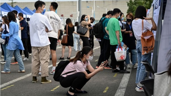 2022 年 8 月 26 日拍摄的照片显示，一名女性在北京的招聘会上使用手机。 