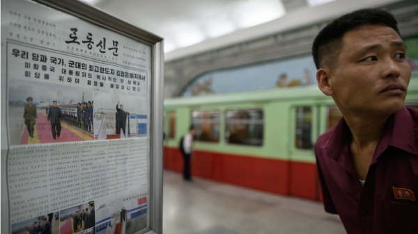 2018年6月12日，在平壤地铁站台的报摊上，一名男子在展示朝鲜领导人金正恩在新加坡与美国总统唐纳德．特朗普会面之前的《劳动新闻》旁边做出反应。
