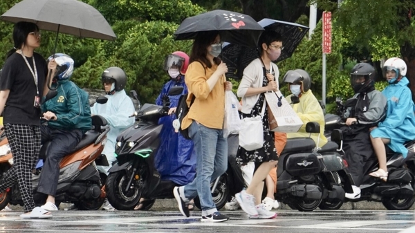 图为高雄市新 兴区10日午后下起阵雨，行人及机车骑士纷纷撑伞、 穿起雨衣
