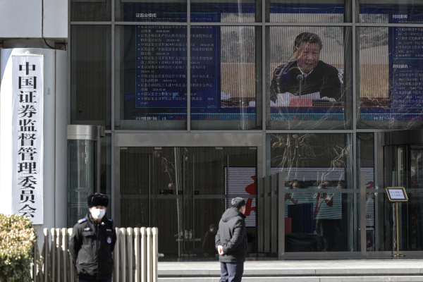 2024年2月8日，保安人員站在中國證監會大樓外，屏幕中的新聞報導顯示了中國國家主席習近平的形象。