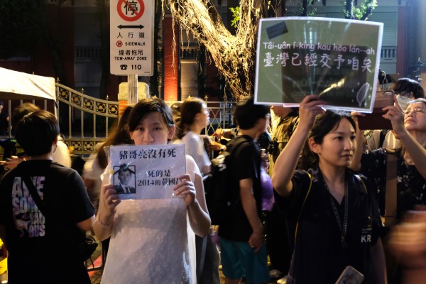 现场有许多民众自制文宣品。图左女性手持“猪哥亮没有死，死的是2014黄国昌”。图右女性手持的是“台湾已经交予咱矣”。