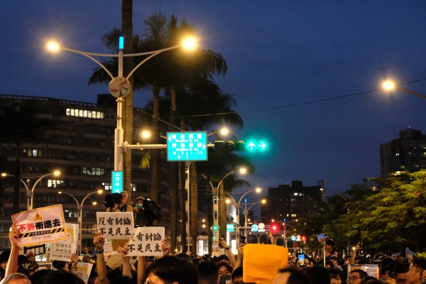 青島東路上，人潮稠密。左下角有民眾舉牌「不要衝進去。注意自身安全。溫柔抗議，不要煽動。」