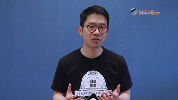 罗冠聪穿着印有香港抗争图案的黑色T恤，在美国民主峰会上发言。（图片来源：视频截图）