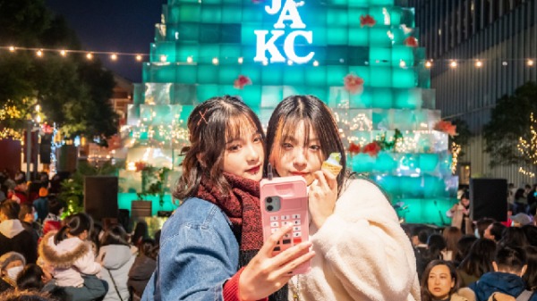 2020年12月24日，两名女子在上海平安夜一家购物中心外的圣诞主题照明装置前自拍。