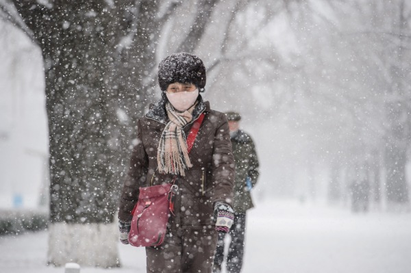 2021年12月18日，朝鮮平壤下雪，一名婦女走在街道上。