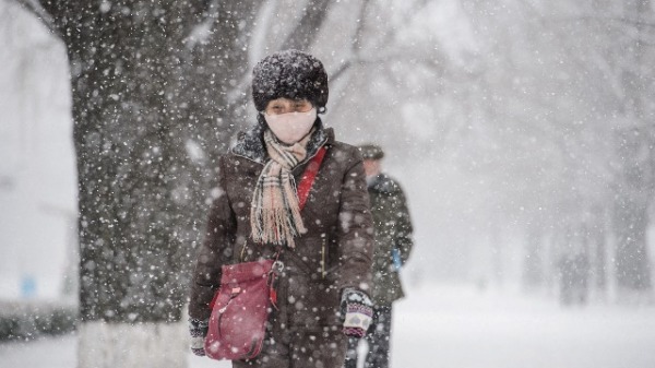 2021年12月18日，朝鮮平壤下雪，一名婦女走在街道上