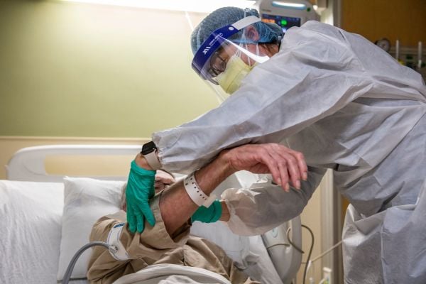 图为2022年1月11日，美国马萨诸塞州西罗克斯伯里（West Roxbury）的美国退伍军人事务部 (VA) 波士顿医疗中心的Covid-19负压病房中，一名患有 Covid-19 的美国陆军退伍军人正在接受医务人员的治疗。（图片来源：JOSEPH PREZIOSO/AFP via Getty Images）