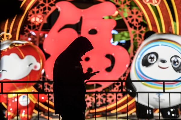 2022年1月15日，在中国北京，一名男子在北京冬奥会吉祥物灯光表演旁查看手机。（图片来源：Di Yin/Getty Images）