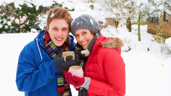 冬天雪地上一對情侶穿保暖衣物喝咖啡