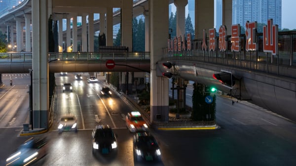 2022年6月1日的上海，汽車和出租車在街上行駛，背景是大幅宣傳標語。