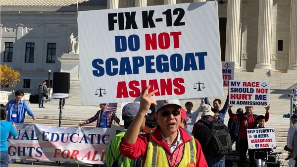 2022年10月30日，一名参与集会的者手持标语板，上写“整顿K-12，不要把亚裔当替罪羊”。（看中国摄影）