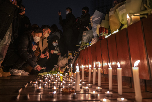 抗議者於2022年11月27日在中國北京抗議中國嚴格的零COVID措施期間，在紀念碑前點燃蠟燭並留下香菸。