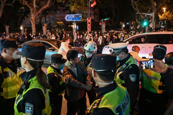 图为2022 年 11 月 27 日晚间，中共警察在上海封锁乌鲁木齐中路时逮捕了一名抗议的男子。11月24日晚间，新疆乌鲁木齐发生致命火灾，中共官方说10人丧生，民间认为有40多人丧生，而且主要原因是防疫封锁堵住了民众的逃生通道并延误了救火车的靠近。消息传出后，大量上海民众聚集到乌鲁木齐中路悼念逝者并反对中共的“病毒清零”封锁政策。（图片来源：HECTOR RETAMAL/AFP via Getty Images）