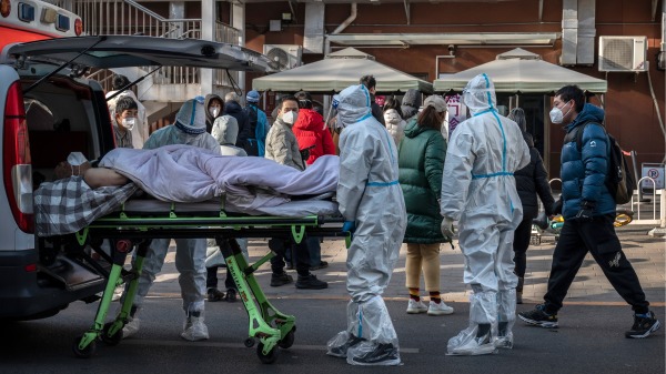 2022年12月9日，北京一家醫院醫護人員，將染疫患者從救護車推下來。（圖片來源：Kevin Frayer/Getty Images）