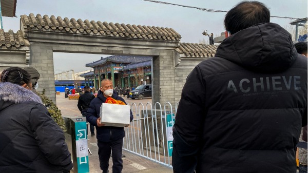2022年12月20日，北京的新冠疫情肆虐，一位北京居民捧着亲人的骨灰走出殡仪馆。（图片来源：NOEL CELIS/AFP via Getty Images）
