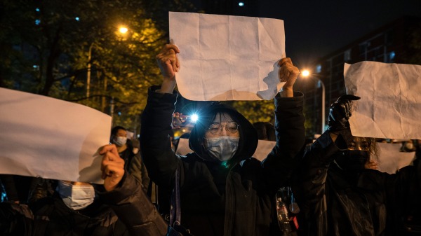 图为2022年11月 27 日，市民在北京游行时举着一张反对审查制度的白纸。