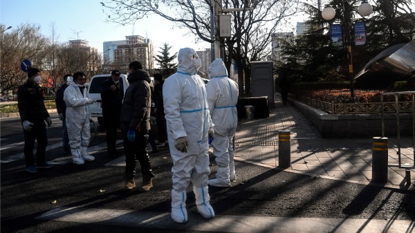 2022 年 12 月 5 日，人们在北京的一条街道上穿着个人防护装备 (PPE)。