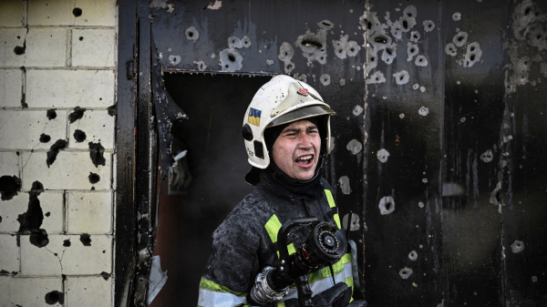 在烏克蘭首都基輔遭到俄軍猛烈攻擊後，一名烏克蘭消防員站在千蒼百孔的房屋前，試圖撲滅屋內的火災。