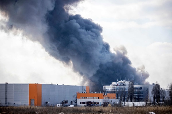 图为2022 年 3 月 24 日，在乌克兰首都基辅的郊外，一座仓库建筑被俄罗斯军队发射炮弹击中冒出浓烟。 （图片来源：FADEL SENNA/AFP via Getty Images）