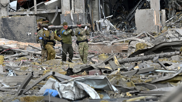 烏克蘭軍人在首都基輔的一棟建築物外清理火箭碎片，該建築物被俄羅斯轟炸摧毀。