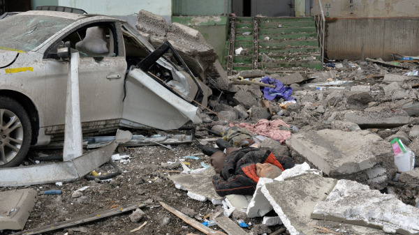 在俄罗斯军队炮击乌克兰第二大城市哈尔科夫后，一名遇难者的尸体躺在一辆被炸毁的汽车旁边