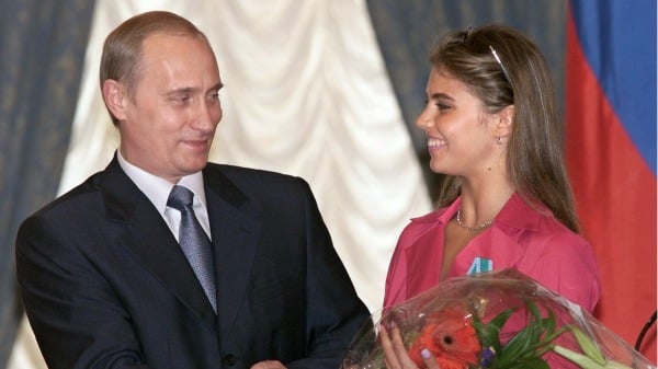 2001年6月8日，俄罗斯总统普京在克里姆林宫举行的年度颁奖典礼上授予奥运会奖得主阿琳娜・卡巴耶娃（Alina Kabayeva）友谊勋章后，向这位俄罗斯艺术体操明星献花。（图片来源：SERGEI CHIRIKOV/AFP via Getty Images)