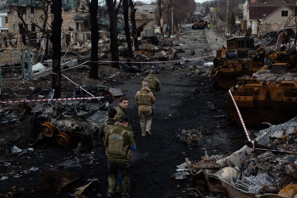 2022 年 4 月 4 日，一队乌克兰军人走在基辅郊区小镇布查（Bucha ）被烧毁的街道上。乌克兰政府指控俄罗斯军队在占领这座小镇时对平民实施了“蓄意的大屠杀”。（图片来源：Anastasia Vlasova/Getty Images）