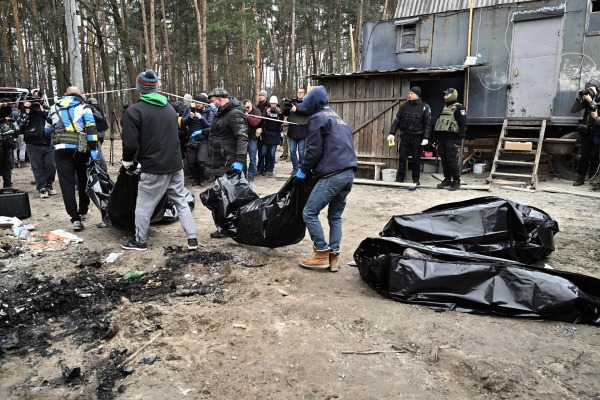 2022 年 4 月 5 日，乌克兰首都基辅的郊区小镇布查（Bucha），市政工作人员把6 具部分被烧毁的尸体装入尸体袋并运走。乌克兰官员表示，从更广泛的基辅地区发现了 400 多具平民尸体，其中许多被埋在尸体坑里。布查小镇一度被俄罗斯军队占领，当俄军最近撤离后，乌克兰政府和包括法新社在内的独立国际记者发现了身着平民衣服的人的尸体，其中一些人的双手被反绑在背后。（图片来源：GENYA SAVILOV/AFP via Getty Images）