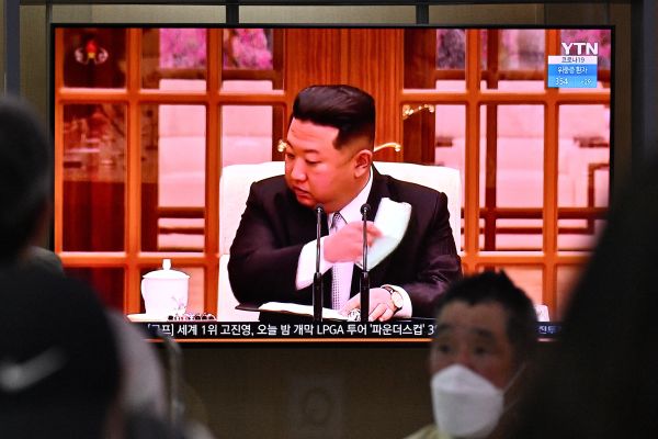 2022年5月12日，人們坐在屏幕旁，看著朝鮮領導人金正恩(Kim Jong Un)在電視上摘下口罩，下令在全國範圍內進行封鎖之新聞廣播。