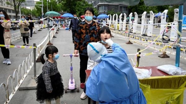 5月11日，在北京街头排队做核酸检测的人们。