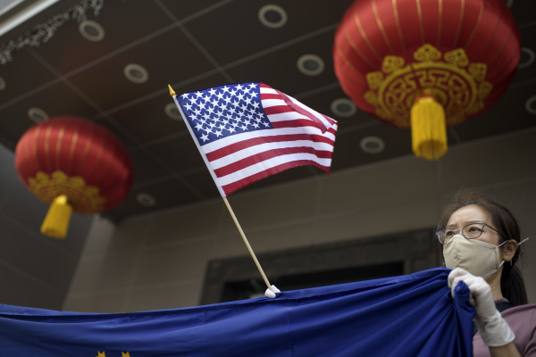 图为2020 年 7 月 24 日，在美国前总统川普政府时期的国务院下令关闭共产中国驻美国休斯顿总领事馆后，一名中共异见人士在该领馆外举着美国国旗以示支持美国的行动。时任国务卿蓬佩奥谴责休斯顿中领馆是中共的“间谍窝”。（图片来源：MARK FELIX/AFP /AFP via Getty Images）