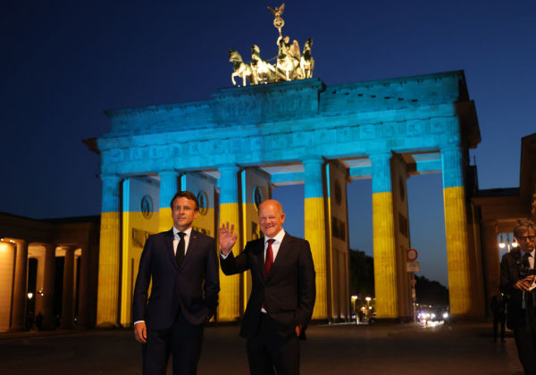 2022年5月9日，在德國柏林，德國總理蕭茲（右）和法國總統馬克龍在總理府會談後，站在被烏克蘭國旗顏色照亮的勃蘭登堡門前。（圖片來源：Sean Gallup/Getty Images）