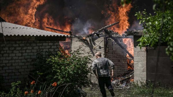 在乌克兰东部顿巴斯（Donbas）地区的吕西昌斯克市（Lysytsansk）遭到炮击后，一名男子从一个着火的车库中跑出来。