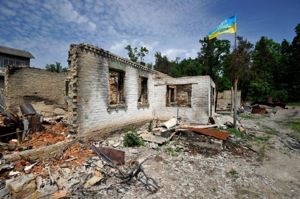 2022 年 6 月 2 日，俄罗斯入侵乌克兰的第 99 天，乌克兰首都基辅郊区小镇莫什春（Moshchun）的一座被俄罗斯炮击摧毁的房屋废墟上飘扬起一面乌克兰国旗。与此同时，战争还在乌克兰东部和南部激烈进行中。乌克兰表示，在俄乌战争第 100 天的前夕，俄罗斯军队控制了乌克兰 20% 的领土。（图片来源：SERGEI CHUZAVKOV/AFP via Getty Images）
