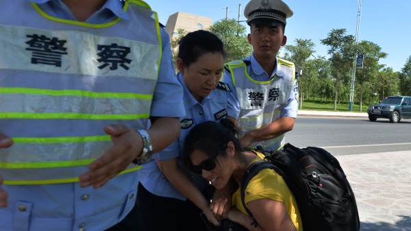 新疆警察在抢夺记者的摄影机。(图片来源：MARK RALSTON/AFP/Getty Images)