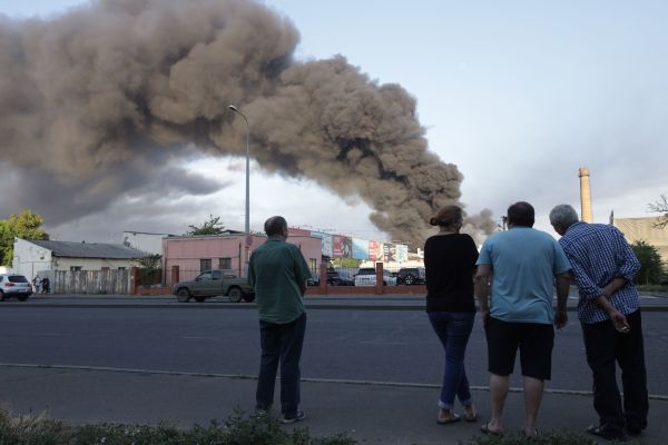 2022 年 7 月 16 日，乌克兰南部港口重镇敖德萨（Odessa），几位居民站在街道上看着远处升起的巨大浓烟，那是俄罗斯的导弹袭击了敖德萨一家工业和贸易公司的仓库后引起的。（图片来源：OLEKSANDR GIMANOV/AFP via Getty Images）