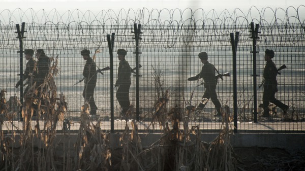 朝鲜士兵在中国边境城镇丹东对面的新义州镇附近的边境围栏旁巡逻