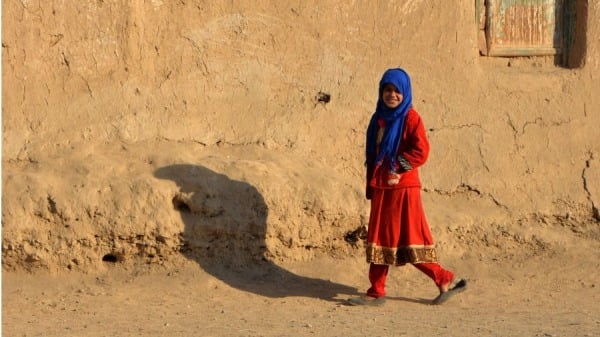 2022 年 1 月 8 日，一名阿富汗女孩走过坎大哈市的一座泥屋
