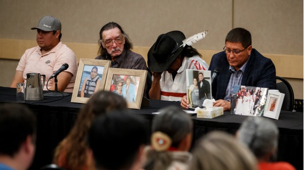 2022年9月7日，在加拿大萨斯喀彻温省萨斯卡通举行的新闻发布会上，杀人案受害者邦妮・伯恩斯 (Bonnie Burns) 的兄弟马克・阿尔坎德 (Mark Arcand) 和邦妮的丈夫布莱恩 (右二) 在邦妮的照片后面。（COLE BURSTON/AFP via Getty Images）