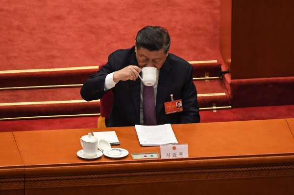 圖為2022年3月8日，中國國家主席習近平出席在北京舉行的全國人民代表大會第二次全體會議期間喝水或喝藥。他的面前與眾不同地擺著兩個茶杯，被外界猜測可能其中一個茶杯裡是藥，因為有關習近平健康出問題的傳聞也不絕於耳。（圖片來源：LEO RAMIREZ/AFP via Getty Images）