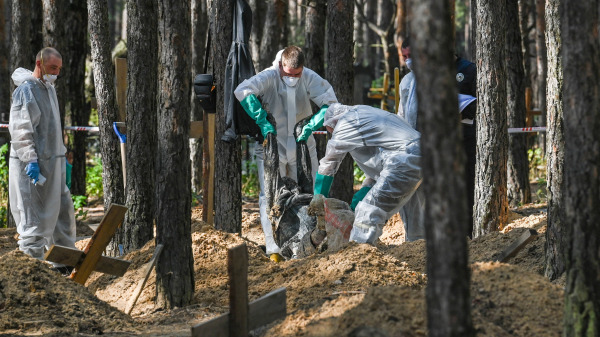 法医技术人员在俄罗斯军队前占领地、乌克兰东部伊久姆（Izyum）市郊区森林中的乱葬坑现场工作。乌克兰发现了大约450个坟墓，其中一些被挖掘出来的尸体显示出遭受酷刑的迹象。