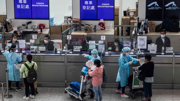 圖為抵達香港機場的入境人士等候被送往隔離酒店。（圖片來源：Getty Images）
