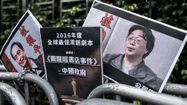 铜锣湾书店5人被失踪，2016年香港人上街请愿并展示讽刺北京当局威逼利诱5人认罪及保平安的海报。（图片来源：Getty Images）