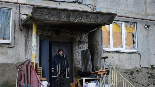 2022年11月13日，烏克蘭索萊達爾（Soledar）一居民站在窗戶破爛的建築門前。