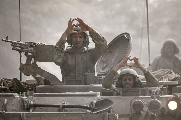 2023年10月13日，以色列士兵坐在一輛沿著以色列南部加沙地帶邊境行駛的裝甲車裡，用手指做出心形手勢。