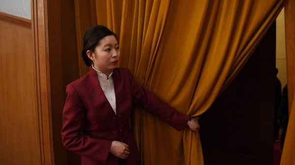 2018年3月3日，在北京大会堂举行的中共政协会议（CPPCC）开幕式上，一名女性工作人员拉着幕布。