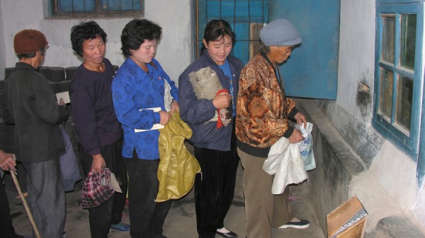 2005年10月17日，朝鲜妇女在朝鲜黄海省北部 Sohung 县的公共配送中心排队领取玉米。