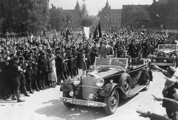 大约1940年，德国独裁者希特勒的车队驶过一条街道，士兵和市民从路边向他致敬。