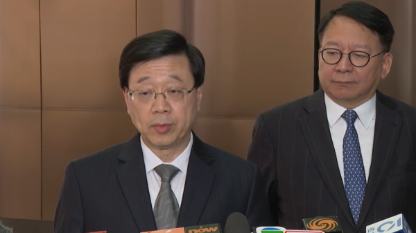 李家超在香港国际机场接受传媒采访，政务司司长陈国基在旁陪同。（图片来源：视频截图）