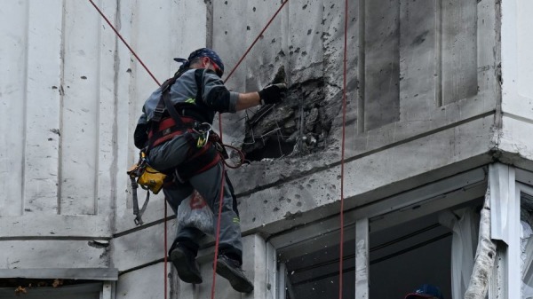 2023年5月30日，在莫斯科发生无人机袭击事件后，一名专家正在检查一栋多层公寓楼受损的外墙